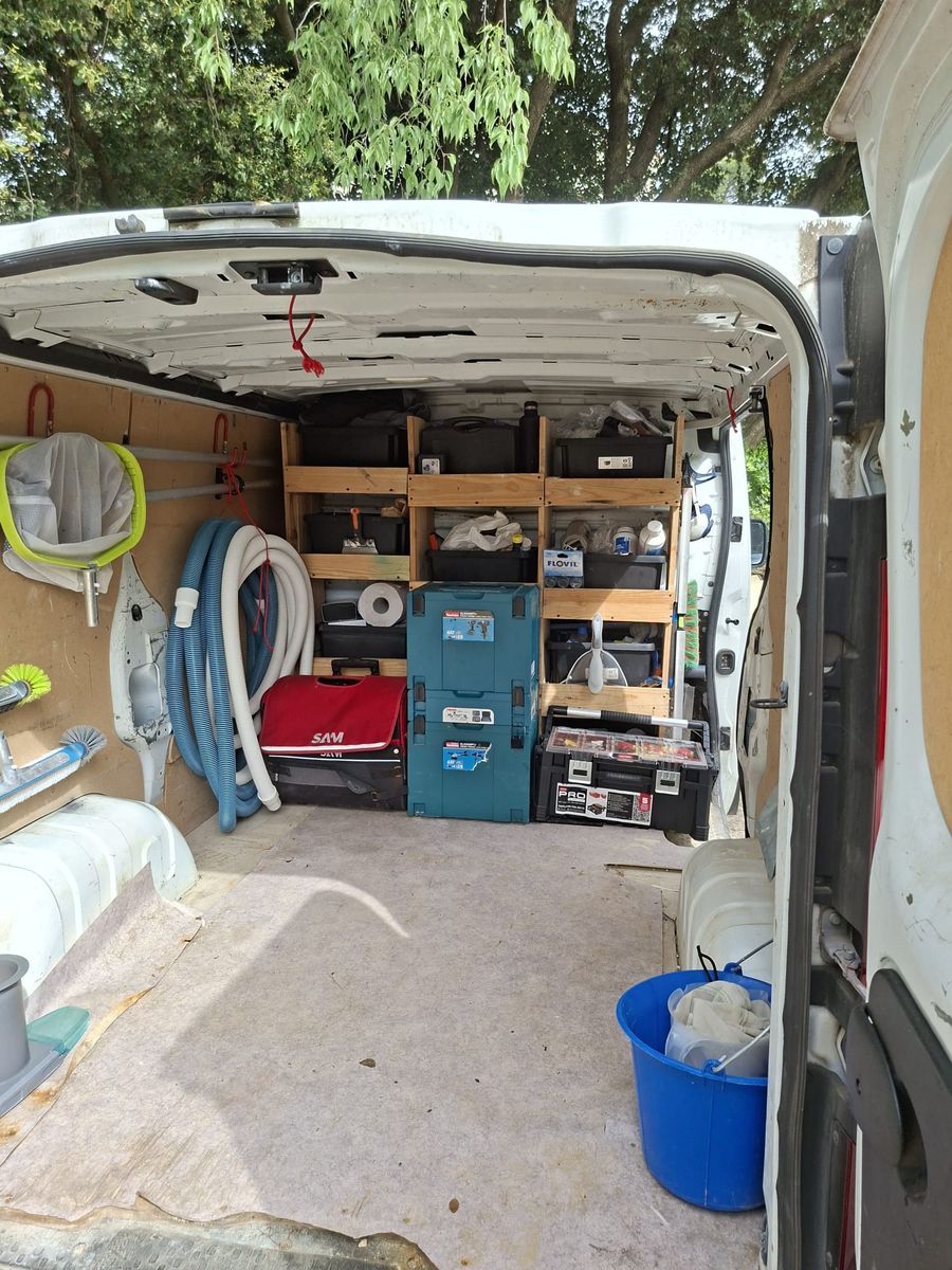 Intérieur de l'utilitaire MA Piscine Associés, aménagé avec étagères, coffres à outils et tuyaux de piscine